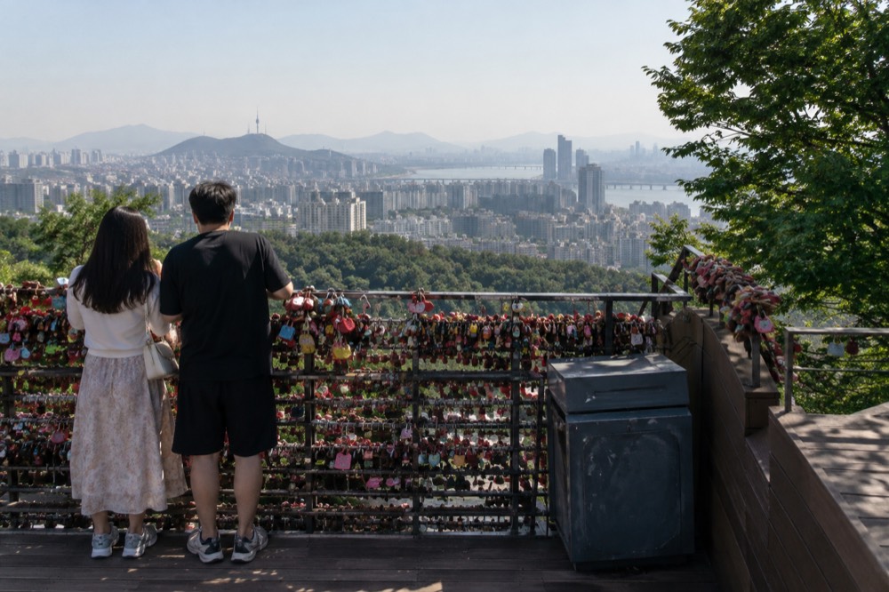 Padlock-covered railings on an open terrace with city buildings visible in the distance below