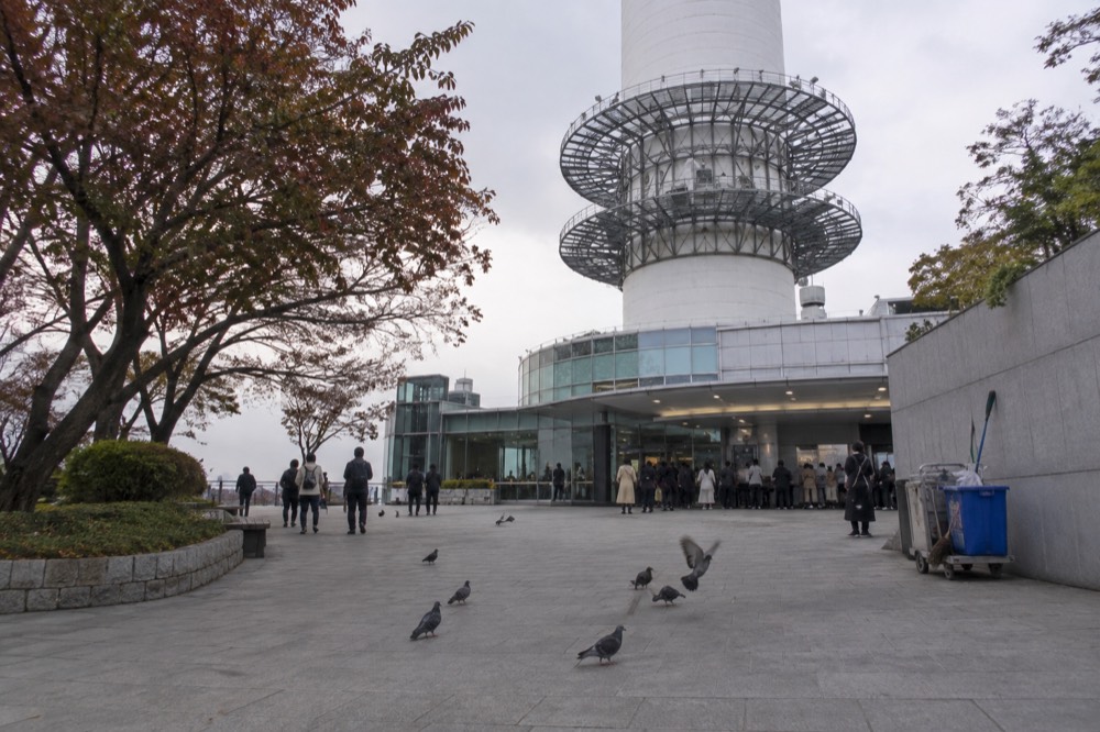 The N Seoul Tower ticket booth area at the tower base with visitors gathering near the entrance