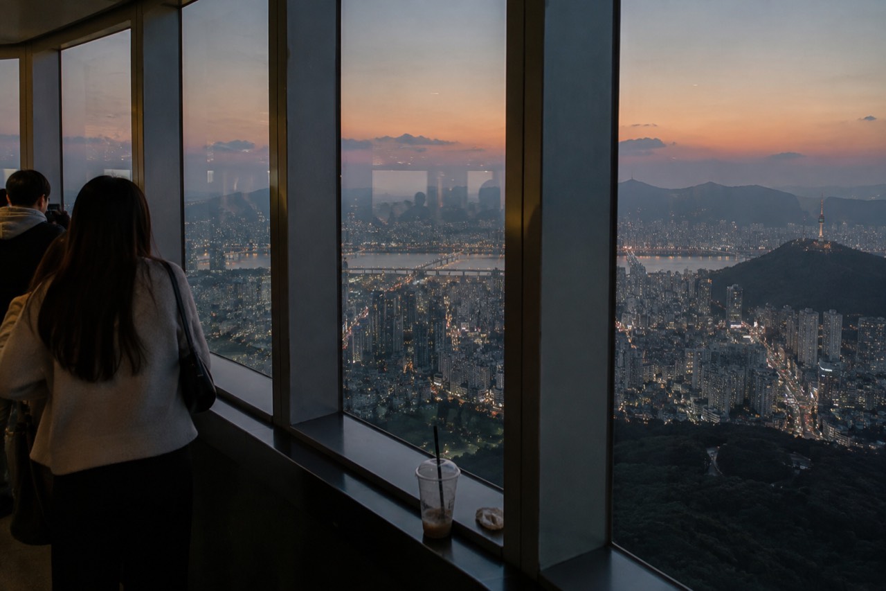 The N Seoul Tower observation deck windows at dusk with the Seoul city skyline spreading out below