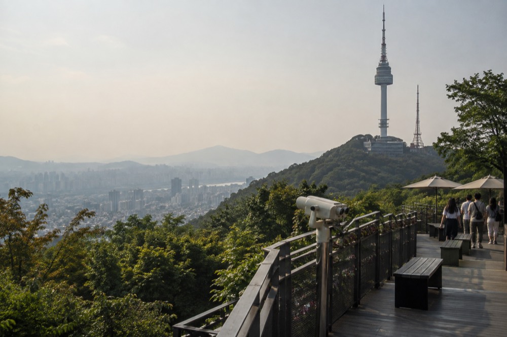 A hazy Seoul skyline seen from the Namsan slopes with the tower rising above the ridge