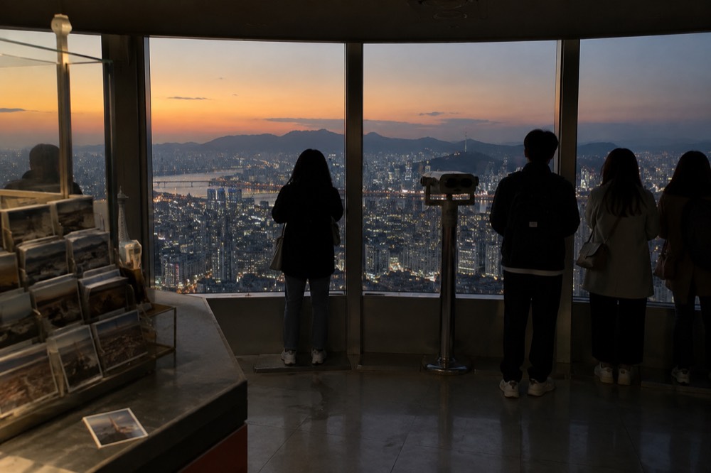 Observation deck interior with panoramic windows overlooking a dense city at twilight