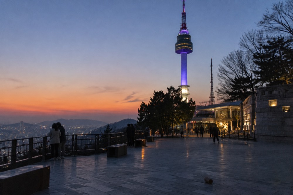 Summit plaza at dusk with N Seoul Tower lit up against a darkening sky