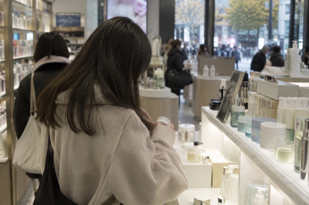 A cosmetics store interior with shelves of skincare products and a lit display counter
