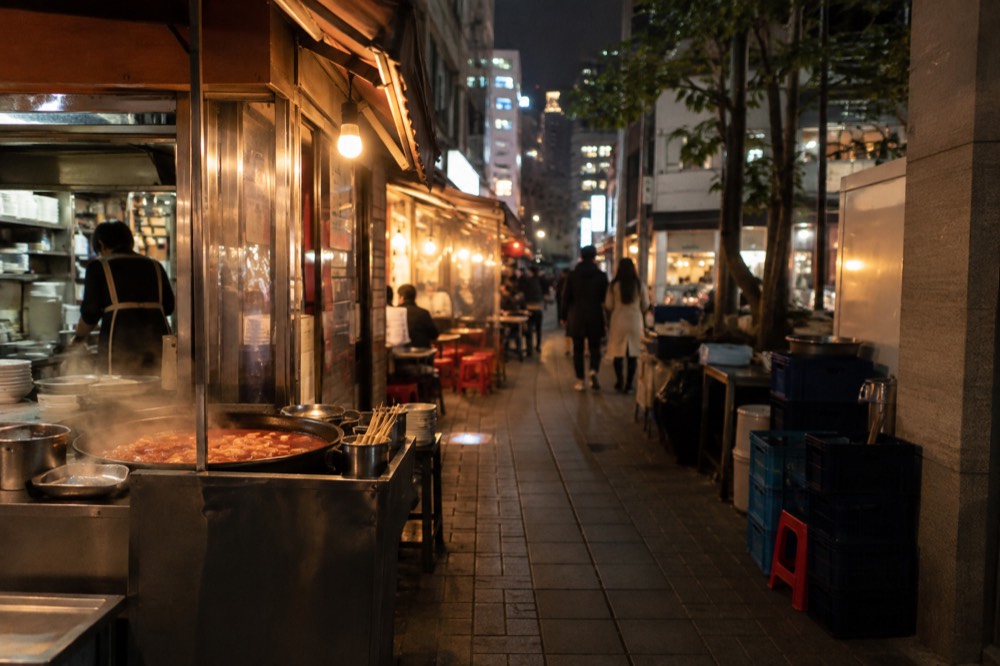 Narrow alley in a Seoul shopping district lined with small eateries and glowing signs at night