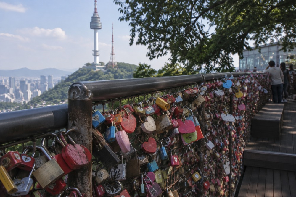 Close view of hundreds of padlocks clipped to wire mesh on a terrace railing