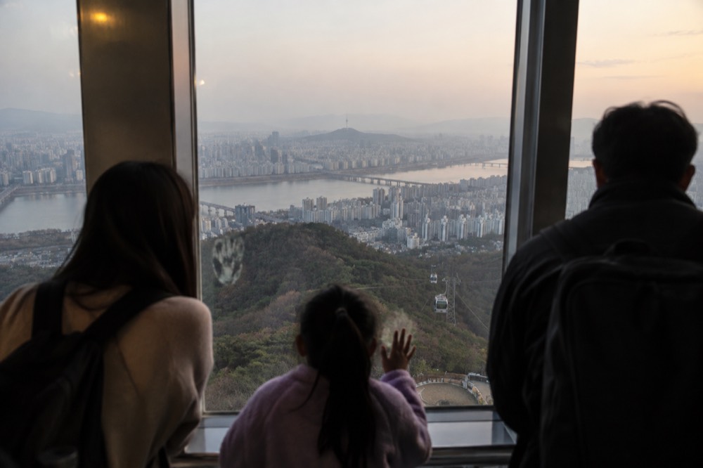 Visitors looking out through the observatory windows over the Seoul skyline