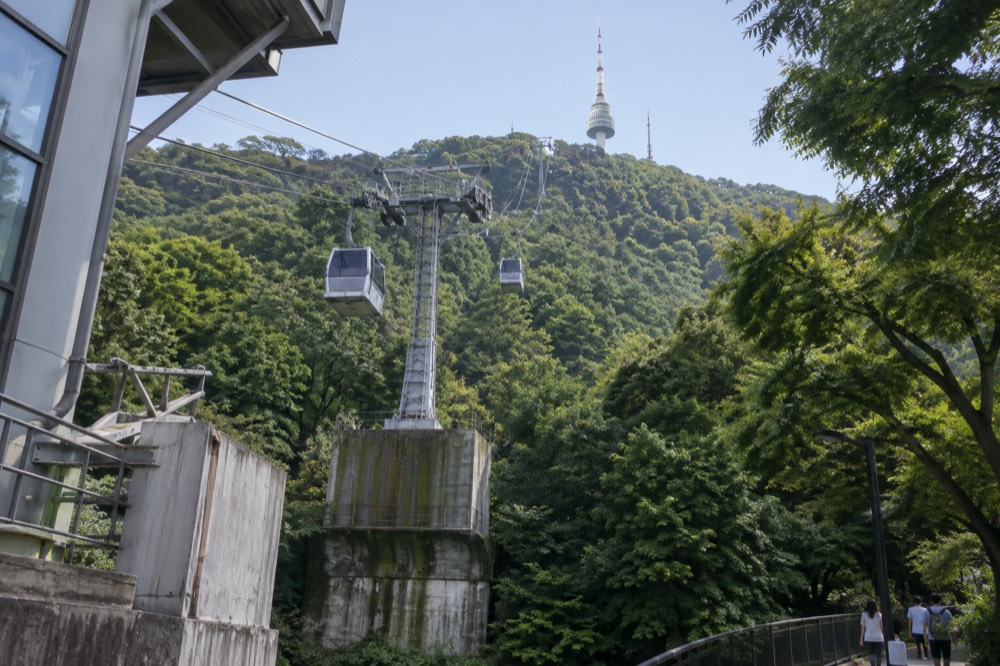 Cable car cabins travelling up the steep forested slope of Namsan toward the tower