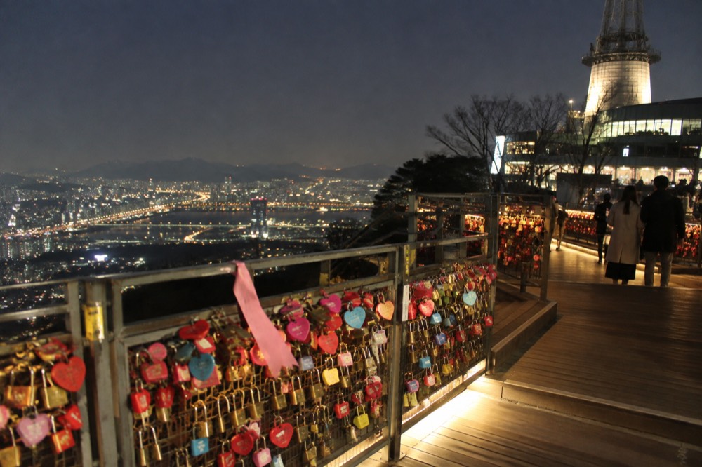 Rows of padlocks covering mesh railings on the love lock deck, lit by warm evening lights