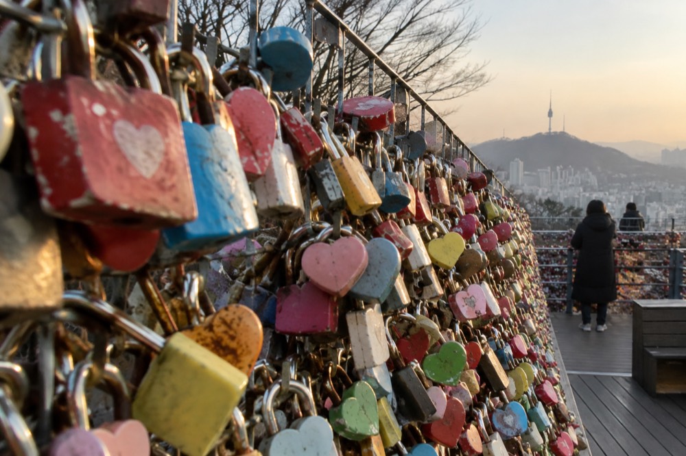 Close view of hundreds of padlocks fastened to wire mesh fencing on an open terrace