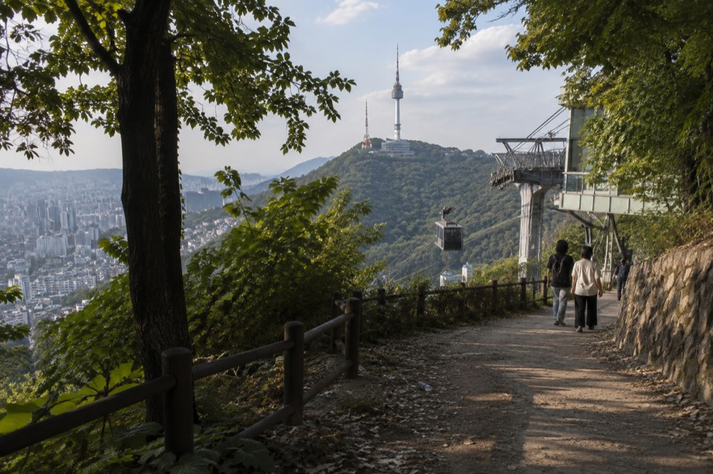 N Seoul Tower seen from a Namsan walking trail with the city spreading out below