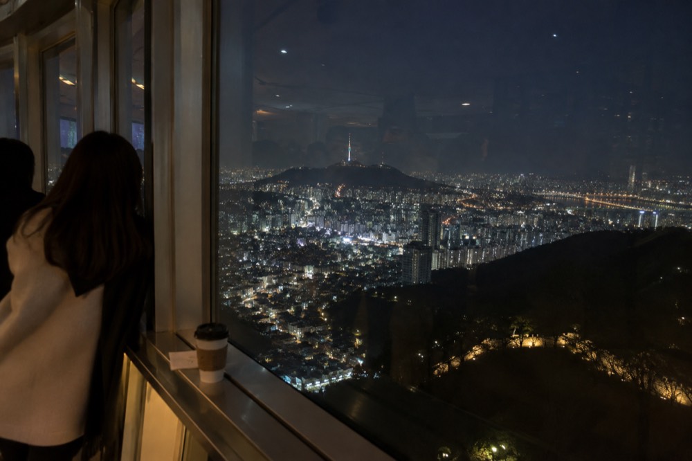 Night view from the N Seoul Tower observation deck over the lit rooftops of central Seoul