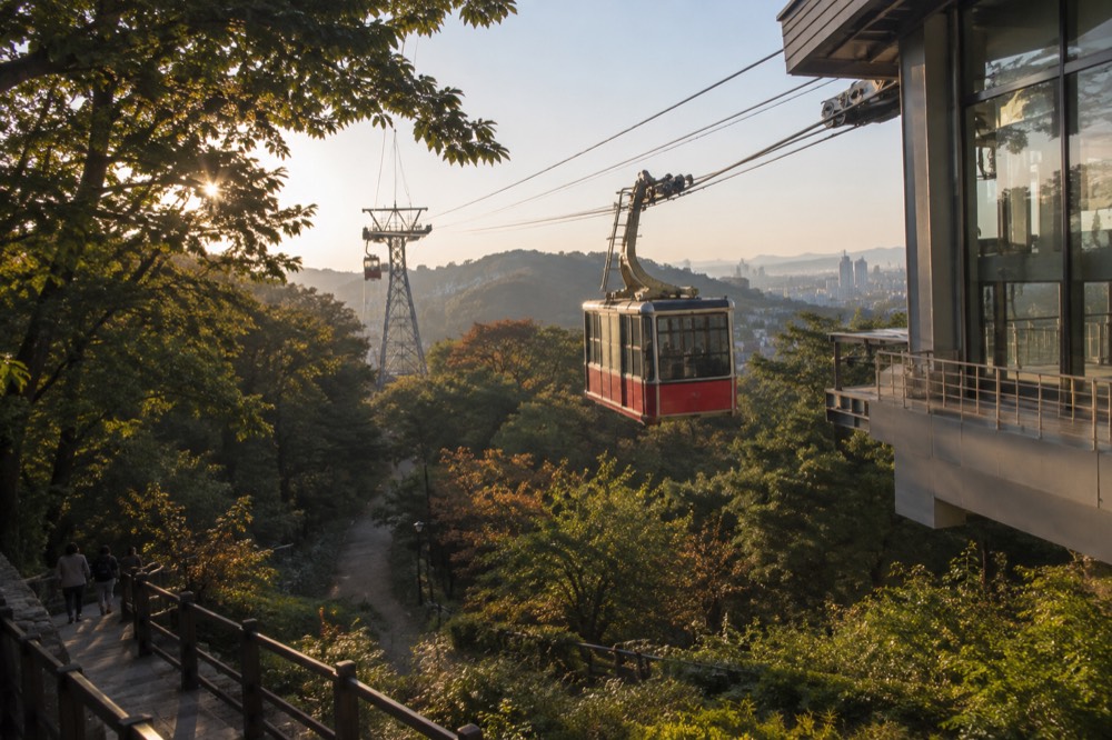 A Namsan cable car cabin travelling up the ropeway toward the tower in late afternoon light