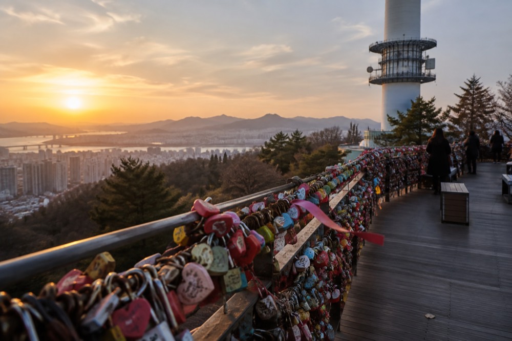 Rows of padlocks attached to railings on the summit terrace with the tower above