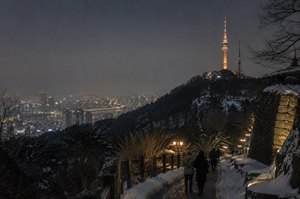 N Seoul Tower illuminated at night above the lights of downtown Seoul