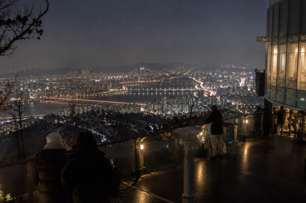 The Seoul skyline at night seen from the Namsan summit with the Han River winding through the city