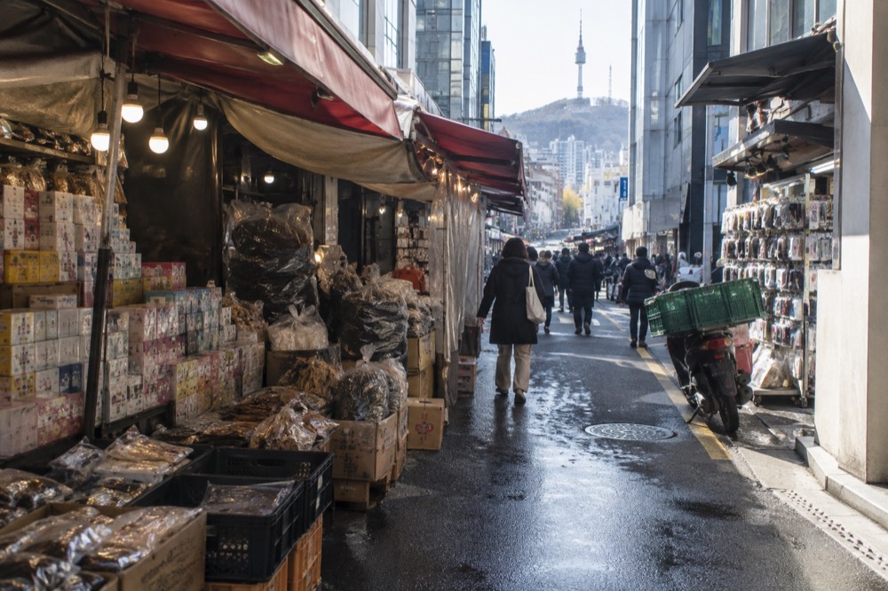 Market stalls under awnings with stacked goods and hanging lanterns