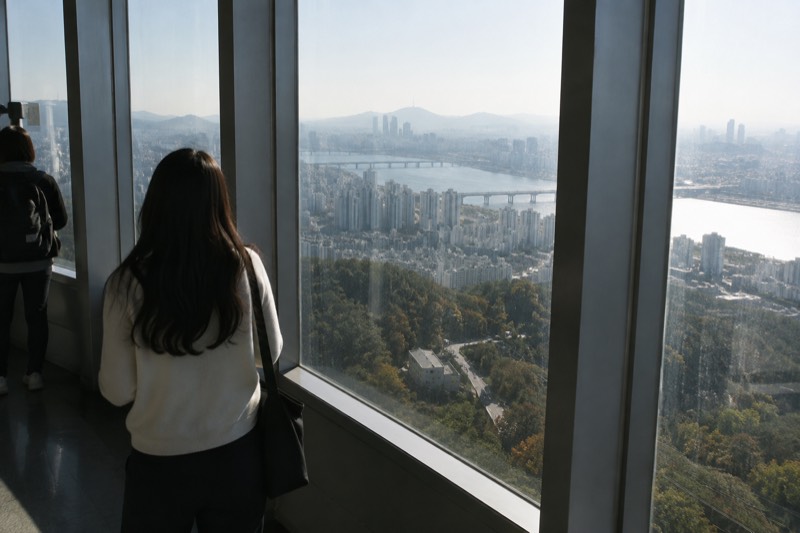 Floor-to-ceiling windows of an observation deck with a dense cityscape spread out below them.